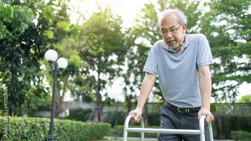 Fotografía Asian Senior disabled man walking slowly with walker or cane at park