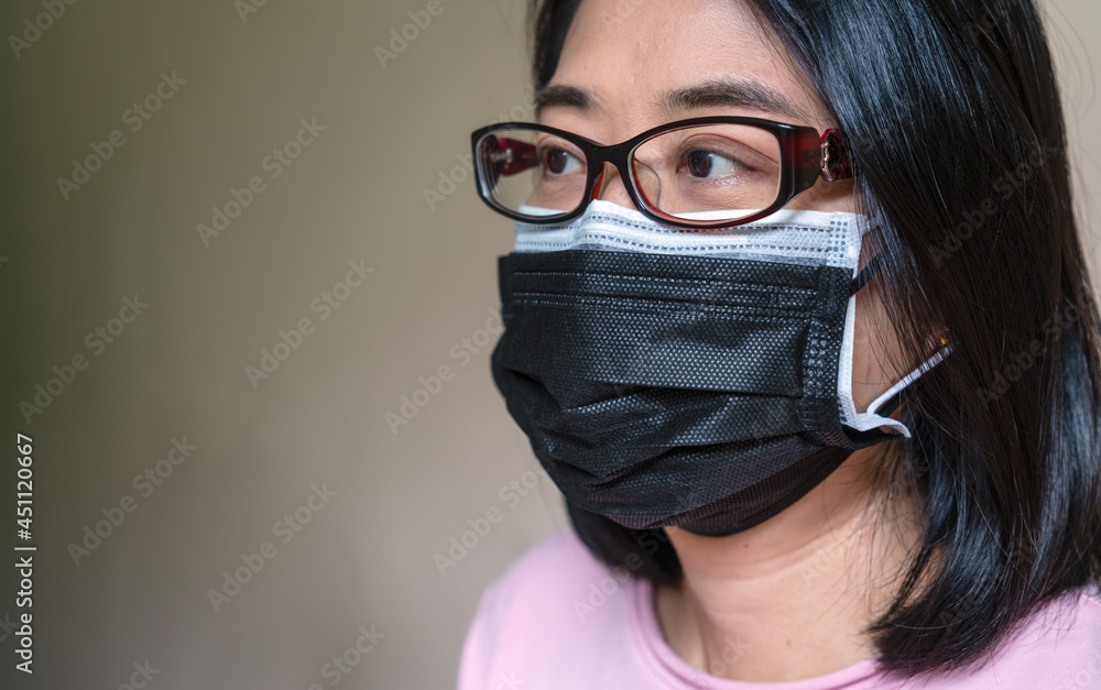 Close up Asian woman face wearing two medical masks together, concept to strongly protect Covid 19 Delta variant virus.