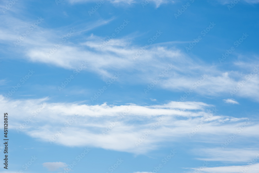 Real Soft Textured Feathery Clouds In Blue Sky Background. On a summer day, feathery fluffy clouds of various shapes and sizes slowly float across the light blue sky.