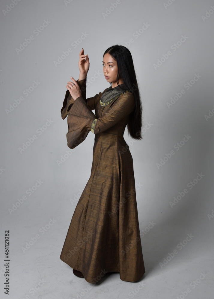 Full length portrait of beautiful young asian woman with long hair wearing medieval fantasy gown costume. Graceful standing posing isolated on studio background. Full length portrait of beautiful young asian woman with long hair wearing medieval fantasy gown costume. Graceful standing posing isolated on studio background.