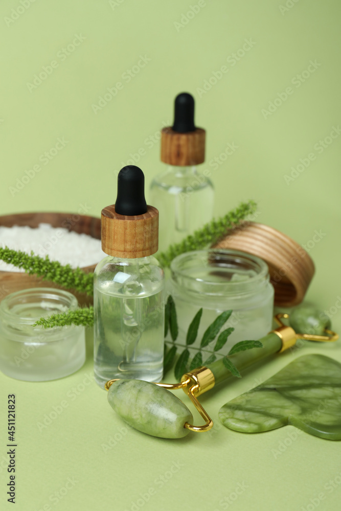 Skin care concept with face roller on green background