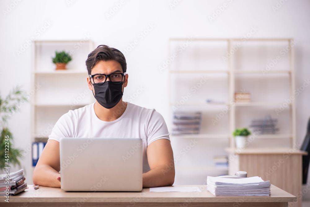 Young male student employee working at workplace during pandemic Young male student employee working at workplace during pandemic