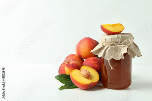 Fototapeta Naklejka Na Ścianę i Meble -  Jar of peach jam and ingredients on white table