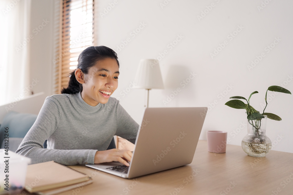 Asian woman using laptop typing work on a table at home Asian woman using laptop typing work on a table at home