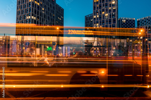 A motion blurred bus with passengers on a illuminated night city street with light trails. Modern public transportation concept background.