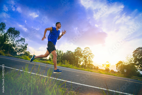 Silhouette of Young man running sprinting on the road. Fit runner fitness runner during outdoor workout with sunset background. Selected focus. 