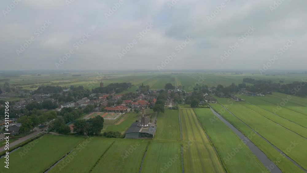 Aerial of a beautiful Dutch, rural town with a spinning scaffolding windmill Aerial of a beautiful Dutch, rural town with a spinning scaffolding windmill