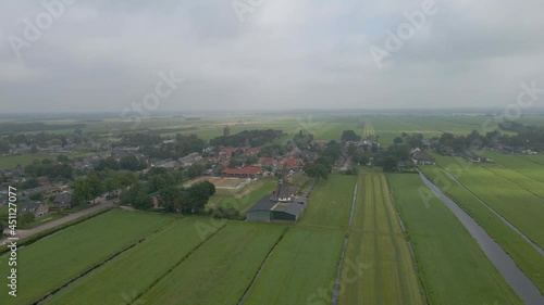 Wide jib down of a old, classic windmill with a small Dutch town in the background photo