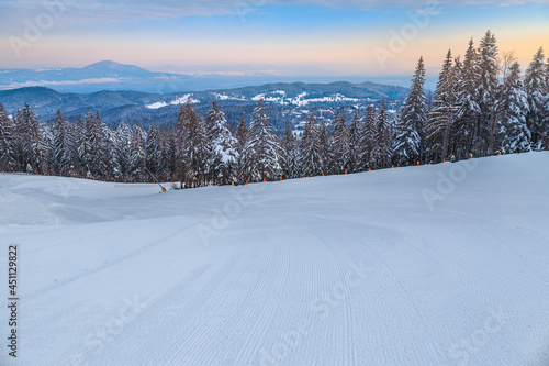 Empty ski slope in the forest at dawn, Romania photo