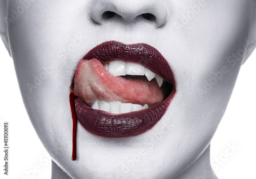 Young woman with bright red lipstick and dripping blood, closeup