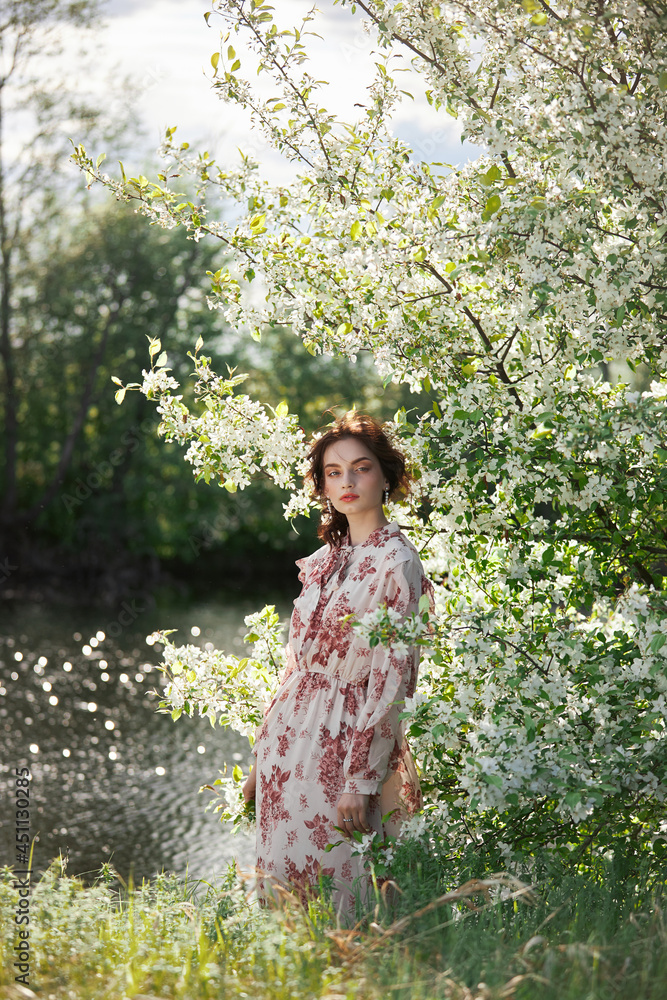Beautiful romantic woman stands in branches of blooming apple tree. Spring portrait girl in flowers apple tree Beautiful romantic woman stands in branches of blooming apple tree. Spring portrait girl in flowers apple tree