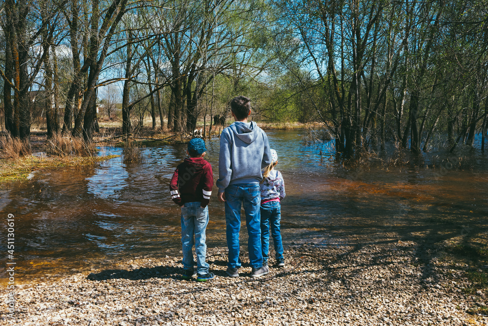 a man with his daughter and son are standing by the flooded river on a rocky beach