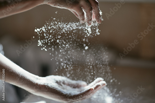 Girl scattering flour in the air, close-up photo of hands