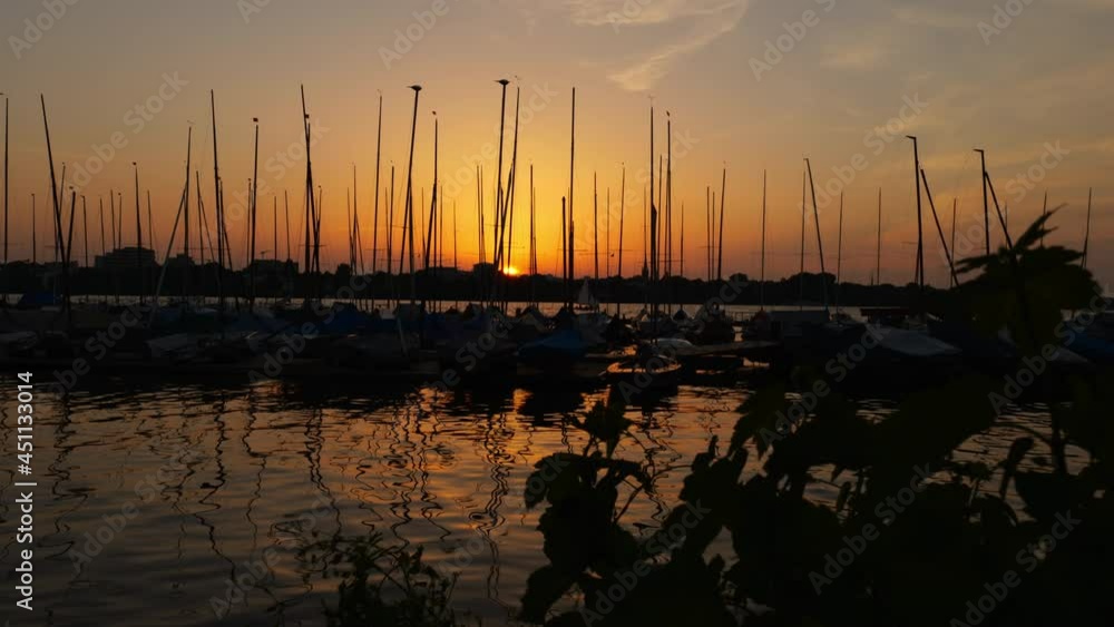 Beautiful steady sunset shot of Außenalster and boats moored at dock while sun sets in Hamburg, Germany. Beautiful steady sunset shot of Außenalster and boats moored at dock while sun sets in Hamburg, Germany.