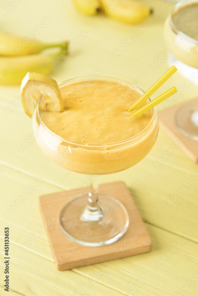 Glass of tasty banana daiquiri cocktail on color wooden background Glass of tasty banana daiquiri cocktail on color wooden background