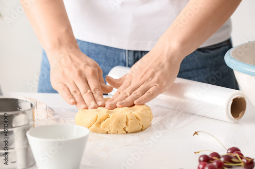 Woman with raw dough for cherry pie at table