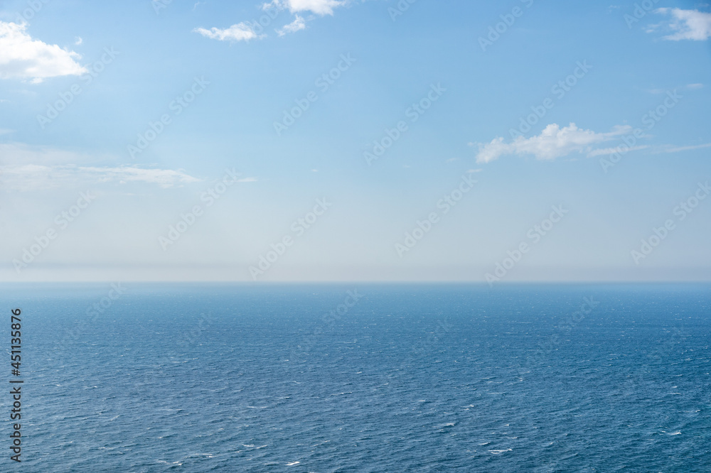 The sea and clouds, through which the sun's rays shine through, reflecting on the surface of the sea on a warm summer day. can be used as a nature background or landscape.