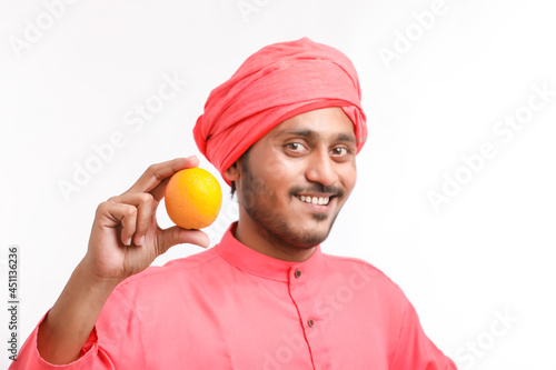 Indian farmer holding an orange fruit in hand over white background. photo