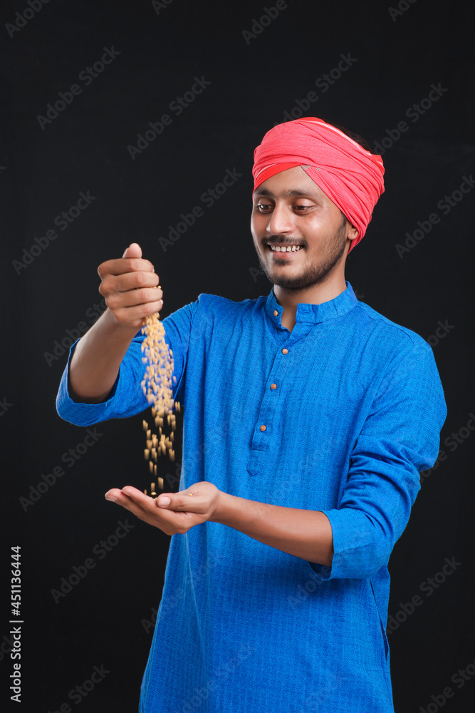 Naklejka premium Indian farmer holding wheat in his hand and smiling.