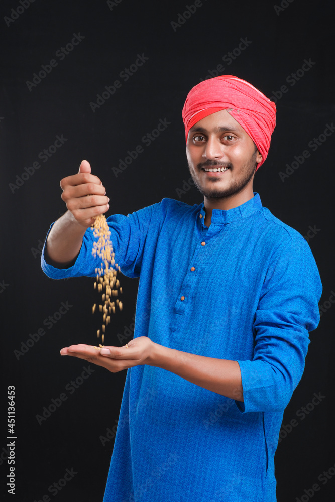 Naklejka premium Indian farmer holding wheat in his hand and smiling.