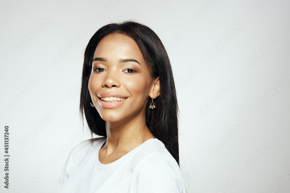 attractive woman of african appearance in a white t-shirt straightens her hair earrings attractive woman of african appearance in a white t-shirt straightens her hair earrings