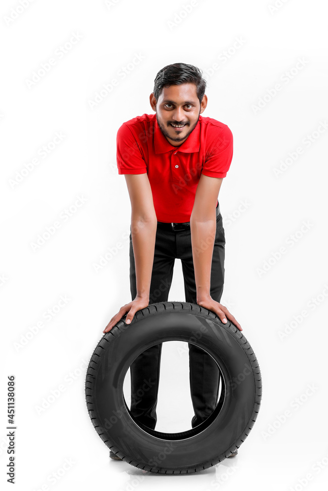 Handsome young male mechanic with new tires isolated on white background. Handsome young male mechanic with new tires isolated on white background.