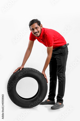 Handsome young male mechanic with new tires isolated on white background.