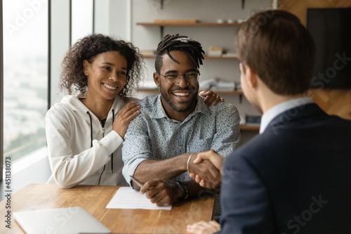 Bilde på lerret Happy young African clients make financial insurance real estate business deal handshake agent or lawyer