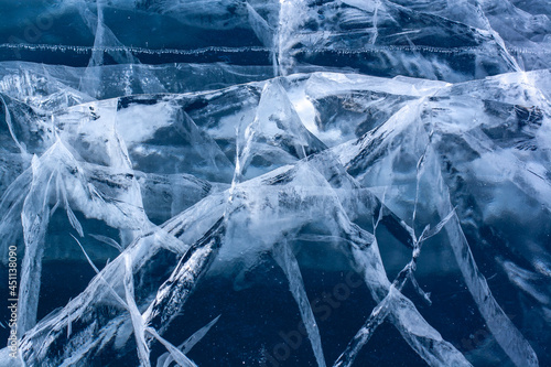 Transparent blue ice with many cracks. The ice is thick. Horizontal.