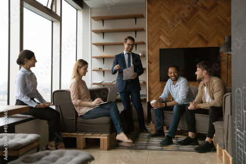 Five young successful happy diverse staff members gathered in office solve current business, consider share ideas. Confident boss in suit led meeting talk to employees. Seminar, team building concept