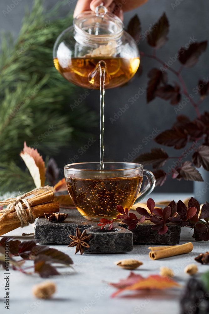Woman pours fresh tea into cup on table with ingredients Woman pours fresh tea into cup on table with ingredients