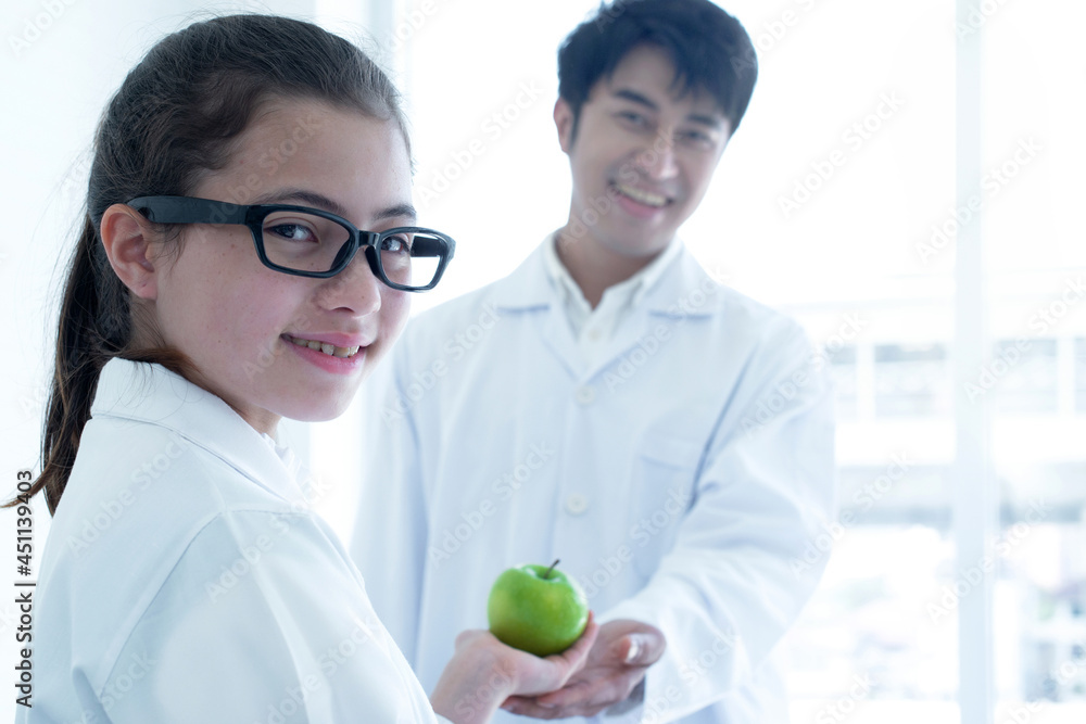 Student giving green apple to science teacher and looking at camera, back to school, selective focus Student giving green apple to science teacher and looking at camera, back to school, selective focus