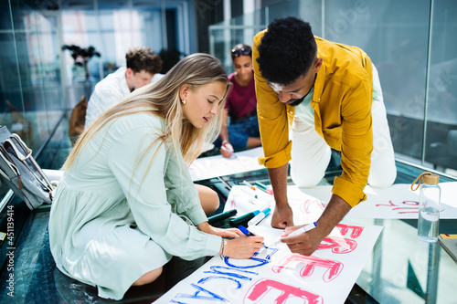 University students activists making banners for protest indoors, fighting for free education concept. photo