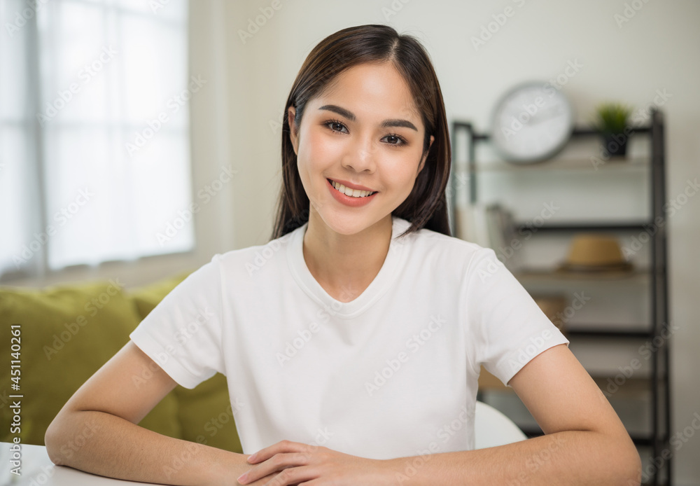Young asian woman looking at camera video conference online sitting in living room at home. Business Woman looking at screen Meeting on social media live steam. Work, learning from home. Young asian woman looking at camera video conference online sitting in living room at home. Business Woman looking at screen Meeting on social media live steam. Work, learning from home.