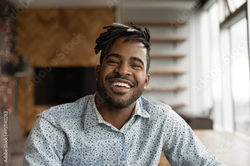 Canvas-taulu African stylish hipster guy with dreadlocks hairstyle wide toothy smile sit indoor look at camera