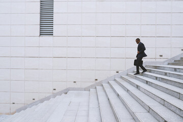 Young financial manager running down the stairs outdoors hurrying to meeting with business partners