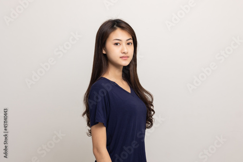 Beautiful young asian woman standing on isolated white background. Thai Teenage girl around 20 looking at camera.
