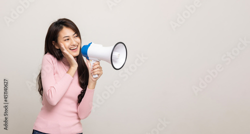 Shout out loud with megaphone. Young beautiful asian woman woman announces with a voice about promotions and advertisements for products at a discounted price. Shopping and fashion concept.
