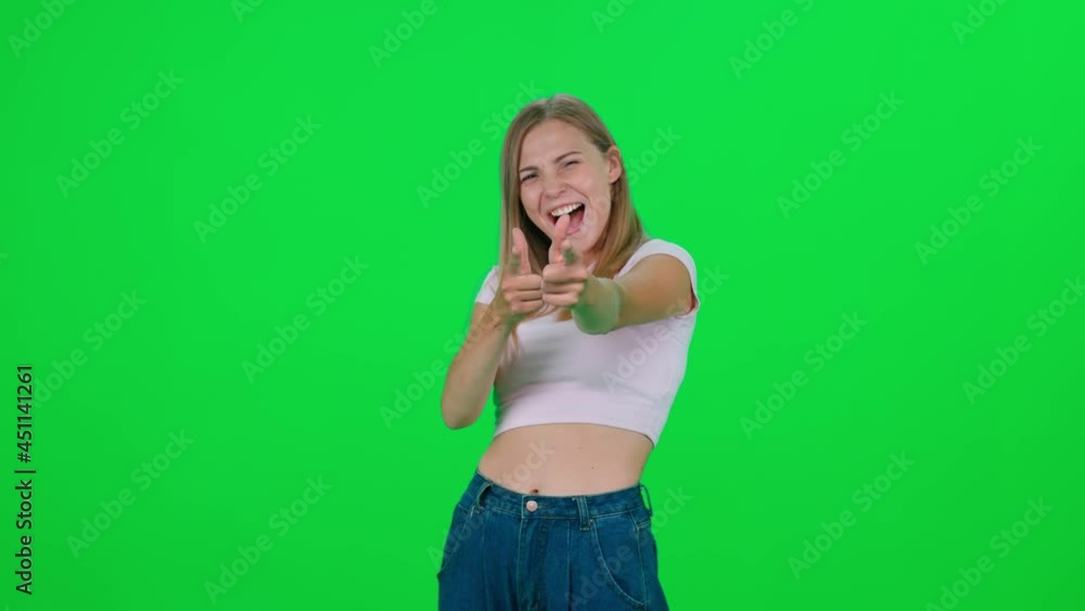 Caucasian female standing in green room and looks at the camera, chroma key background, the young blonde woman points at the viewer and smiles, positive emotions, 4k slow motion. Caucasian female standing in green room and looks at the camera, chroma key background, the young blonde woman points at the viewer and smiles, positive emotions, 4k slow motion.