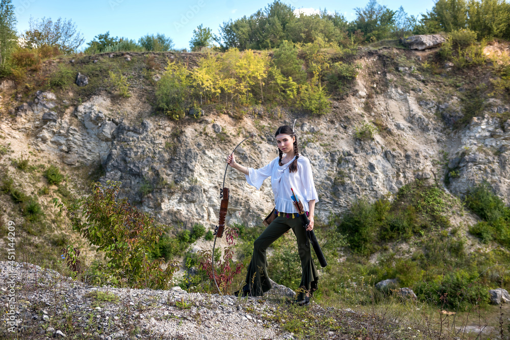Fototapeta premium indian woman poses in a nature surrounding with arrow and bow