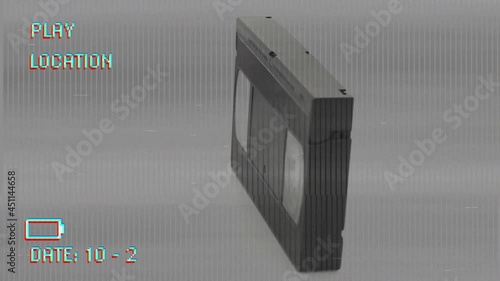 Animation of video cassette rotating on playback interface, with interference, on grey background