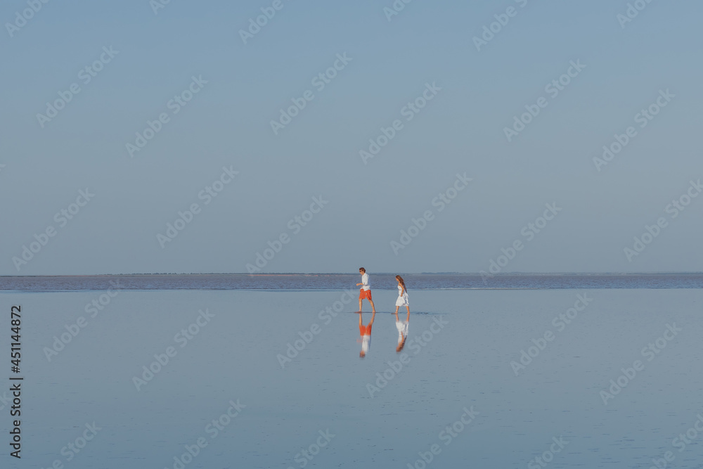 A man and a woman walk on the smooth water of the lake