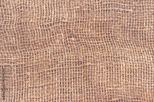 Natural burlap with large cells. The texture of a coarse woven fabric with mesh and fibers.