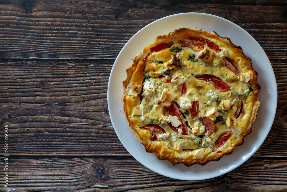 Delicious homemade quiche with feta cheese, tomato, spinach and onion. Homemade puff pastry quiche on the parchment paper. Weathered plank barn wood background top view. Copy space.
Delicious homemade quiche with feta cheese, tomato, spinach and onion. Homemade puff pastry quiche on the parchment paper. Weathered plank barn wood background top view. Copy space.