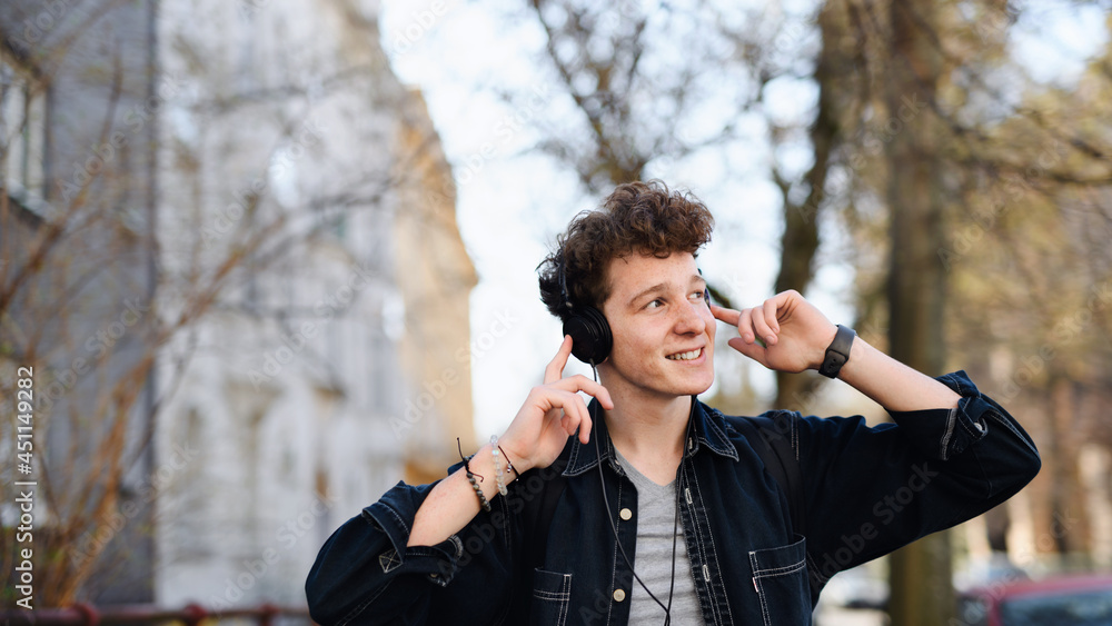 Portrait of young man commuter with headphones walking outdoors in city, listening to music. Portrait of young man commuter with headphones walking outdoors in city, listening to music.