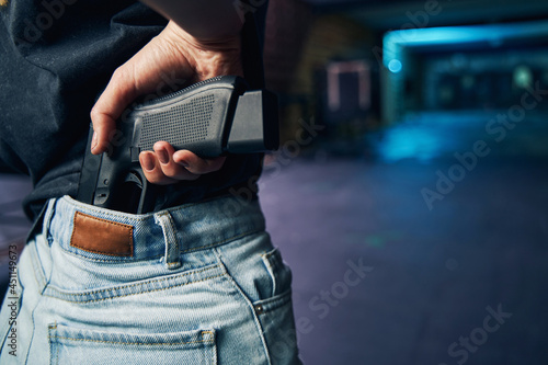 Obraz na plátně Experienced policewoman hiding her firearm in her trousers