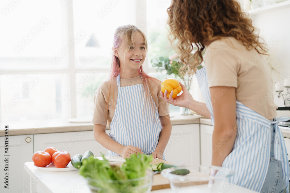 Mother and teen daughter preparing vegetable salad at kitchen Mother and teen daughter preparing vegetable salad at kitchen