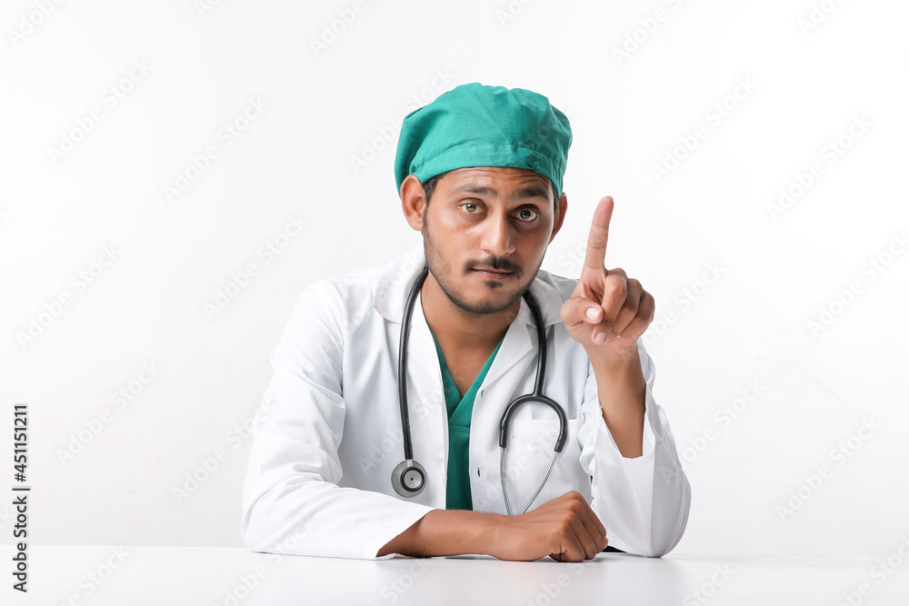 Young indian male doctor in uniform and pointing with hand at clinic. Young indian male doctor in uniform and pointing with hand at clinic.