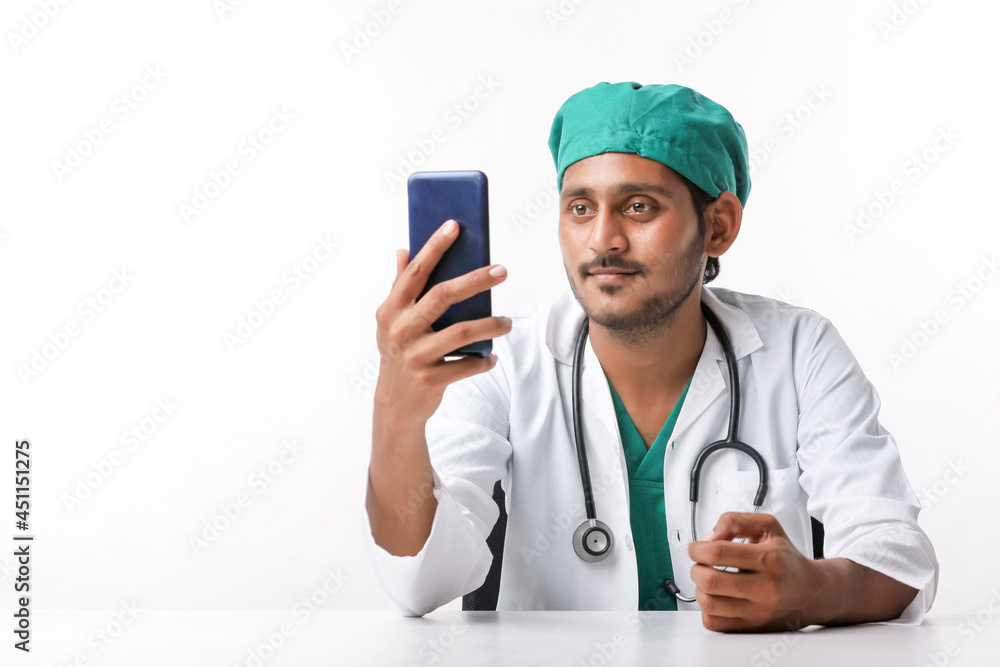 Young indian male doctor using smartphone at clinic. Young indian male doctor using smartphone at clinic.
