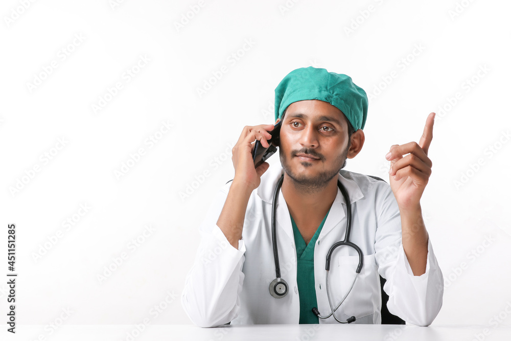 Young indian male doctor talking on smartphone at clinic. Young indian male doctor talking on smartphone at clinic.
